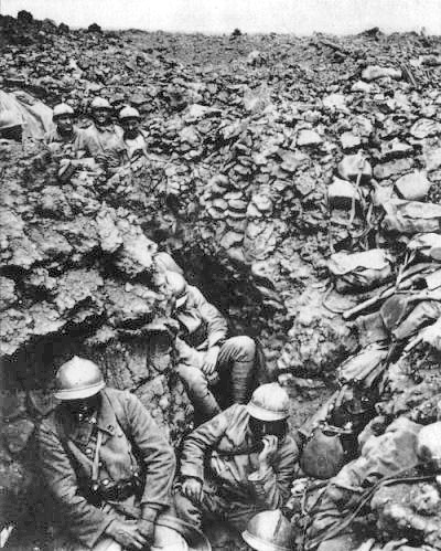 Soldados franceses del regimiento 87 en el monte 304 en Verdún. Se aprecian los cascos, fornituras, las polainas de uno de ellos y montones de mochilas de campaña a un lado de la trinchera. Esta fotografía pertenece al dominio público en los Estados Unidos de América.